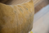 Textured surface of the antique Chinese rug fragment pillow in soft gold with subtle patina.