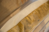 Patinaed gold antique Chinese rug fragment pillow side with woven beige backing.