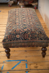 Antique Persian Fereghan rug fragment ottoman side, with geometric borders and dark turned wooden legs.
