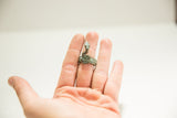 Vintage African bronze snake ring with a green patina shown on a hand to scale.