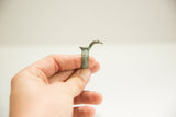 Side view of a vintage cast bronze snake ring with a textured band and green patina.