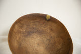Aged wooden African bowl rim with brass repair and visible crack.