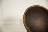 The textured, hand-carved details along the dark wood rim of a vintage bowl.