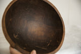 Aged patina and dark wood grain on the interior of a vintage African bowl.