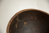 Interior detail of a vintage wooden bowl showing a crack, repair, and aged texture.