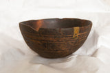 A storied metal staple repair on the dark, hand-carved vintage African bowl.