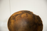 Aged primitive wooden African bowl showing natural amber tones and its uniquely chipped, uneven rim.
