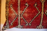 Detail of hand-knotted Turkish Oushak pillow in faded red with geometric tribal pattern.