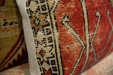 Hand-knotted vintage rug fragment pillow with earthy geometric design and textured fabric edge.
