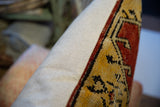 Pillow side with textured beige fabric and hand-knotted red, gold, black Turkish Oushak fragment.