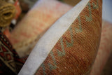 Vintage rug fragment pillow: hand-knotted orange sage pile texture, herringbone border.