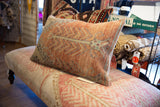 Close-up of textured vintage Oushak pillow pile with muted coral and teal geometric pattern.