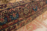Antique Kerman rug fragment pillow texture, showing stylized patterns in muted red, blue, and tan.