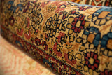 Textured antique Kerman rug fragment pillow with ruby, sapphire, and gold floral patterns.