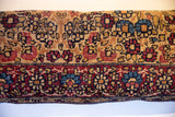 Vintage Kerman fragment pillow showing ruby red, sapphire blue, and gold floral motifs.