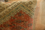 Close-up of the antique Mir Serbend rug fragment pillow, highlighting small rust red and green woven motifs.