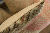 Vintage rug fragment pillow with textured hand-knotted pile and natural beige canvas seam.