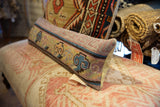 Hand-knotted vintage rug fragment pillow end, displaying colorful motifs in blue, purple, yellow, and cream backing.