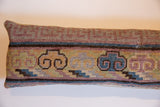 Detailed view of the Khotan rug fragment pillow's textured weave with faded blue and brown bands.