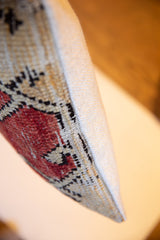 Vintage rug fragment pillow side, showcasing hand-knotted red Oushak pattern and woven backing.