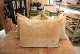 Hand-knotted texture on the vintage rug pillow's edge, showing muted peach, ivory, and faint blue.