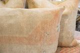Hand-knotted vintage rug fragment pillow, detailed texture with faded peach and subtle blue.