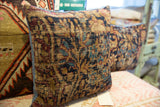 Textured vintage Kerman rug fragment pillow, displaying faded botanical pattern and blue side trim.
