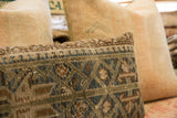Vintage rug fragment pillow close-up of muted geometric pattern and hand-knotted texture.