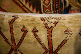 Hand-knotted texture of a vintage rug pillow, showing geometric motifs in beige and red.