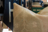 Close-up of hand-knotted vintage rug fragment pillow in muted beige with faded details.