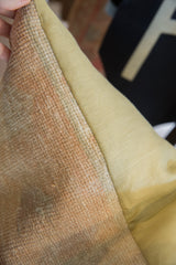 Vintage rug fragment pillow texture: faded hand-knotted peach pile and smooth pale green fabric.