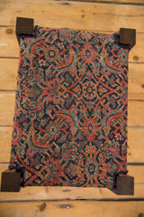 Overhead view of the footstool's antique Persian Herati rug pattern top in red and navy.