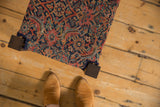 Overhead view of the footstool's antique rug upholstery with a red and blue Herati pattern.