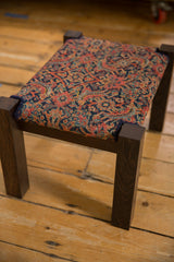 Antique footstool featuring a Persian Herati rug fragment top on a dark wenge wood frame.