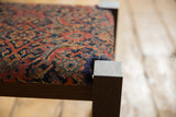 Corner detail of the footstool showing the antique Herati rug fragment and wenge wood leg.