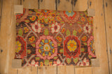 Top-down view of a footstool showing the colorful geometric pattern of the antique rug fragment.