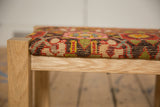 Close-up of the solid oak frame and textured wool top of an antique rug fragment footstool.