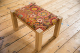 Handmade oak footstool upholstered with the textured reverse of a colorful antique rug fragment.