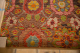 Close-up of the antique rug fragment's detailed hand-knotted texture on the footstool's corner.