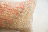 Faded coral, beige, and sage colors on the thick hand-knotted vintage rug pillow.