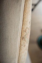 Textured vintage rug fragment side and beige woven backing of a pillow.
