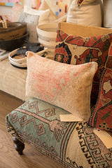 Handmade vintage rug fragment pillow displaying soft peach and subtle blue-green texture.