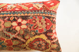 Detailed hand-knotted texture and tribal red, teal, cream pattern on a vintage rug fragment pillow.