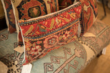 Side view of vintage rug fragment pillow with intricate hand-knotted red, blue, cream patterns.