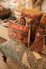 Vintage rug fragment pillow corner, showing rich red, blue, and cream patterns.