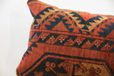 Geometric patterns on vintage rug fragment pillow in textured rust, navy, and tan.