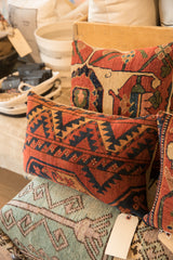 Vintage rug fragment pillow featuring bold geometric pattern in rust, navy, and gold.