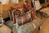A collection of handmade vintage rug fragment pillows with varied geometric and traditional patterns.