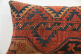 Hand-knotted texture and geometric tribal pattern on a vintage rug fragment pillow in red and blue.