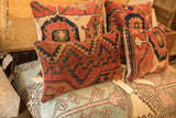 Intricate geometric pattern of a vintage rug fragment pillow in brick red and deep blue.